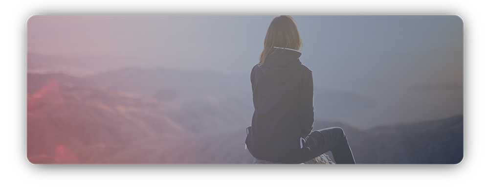 Woman sitting on top of a hill outdoors hiking and looking at landscape